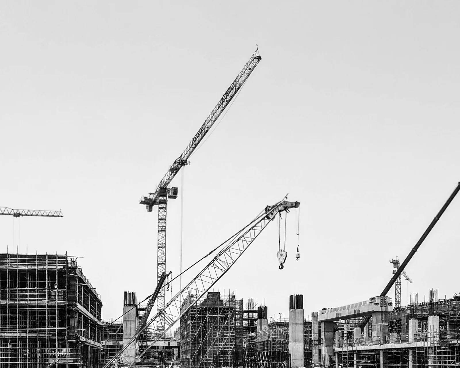 Tower cranes over a concrete frame, high-key monochrome